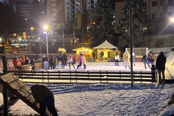 Immagine in notturna del pattinaggio su ghiaccio con pattinatori.